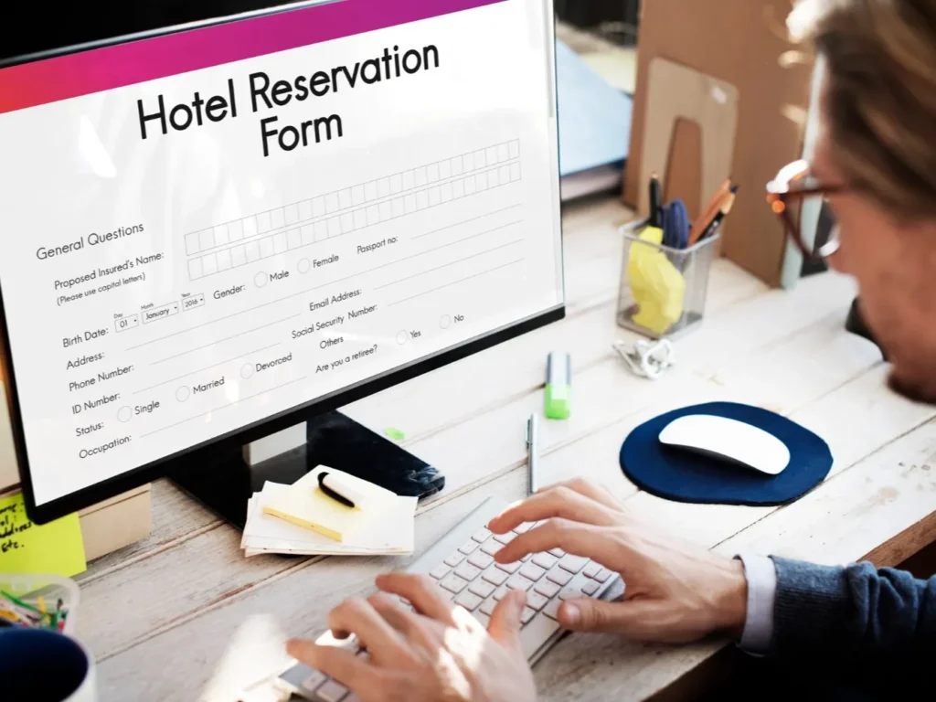 Pracownik hotelu wprowadza dane gościa do formularza rezerwacji na komputerze.